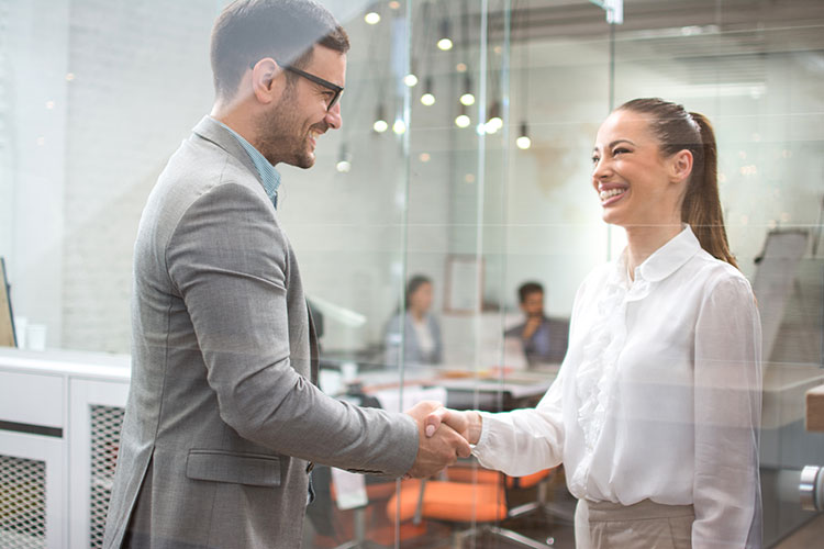 business man and business woman shaking hands in an office