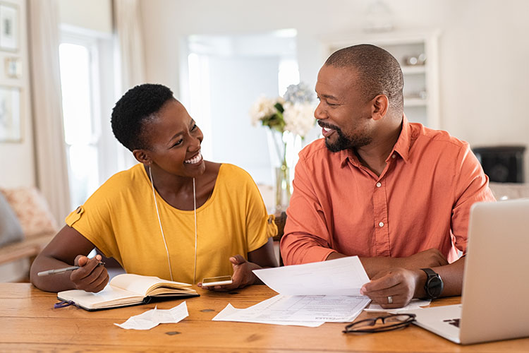 african american couple working on taxes and smiling at each other
