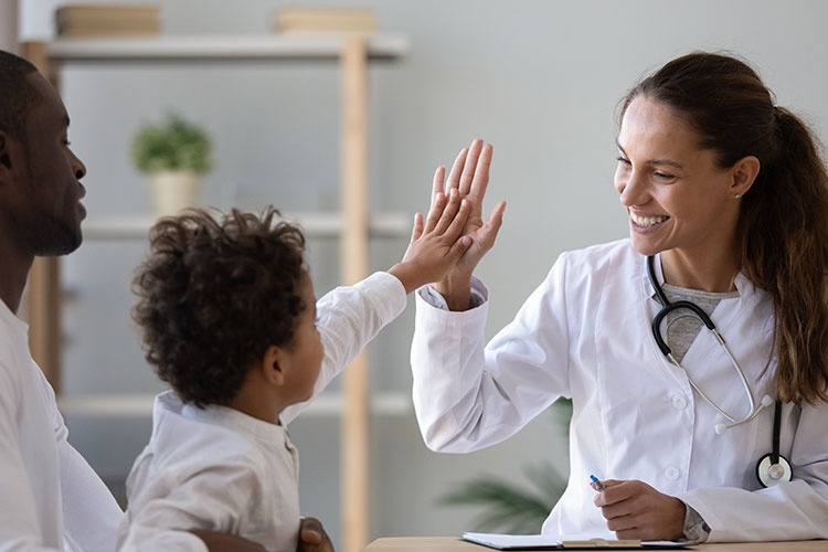 young child giving a high five to her doctor