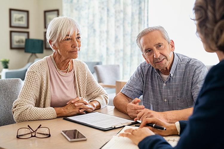 elderly couple sitting and discussing finances with financial planner