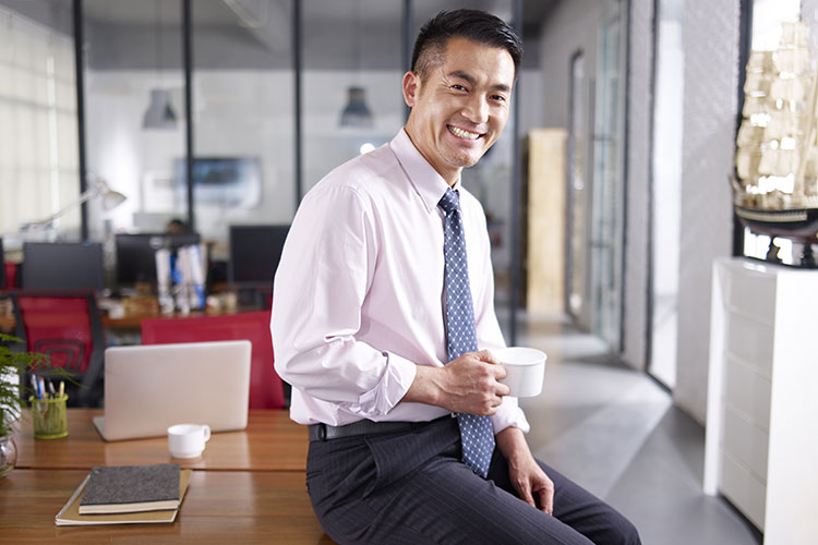 young asian business man holding a mug in his business office